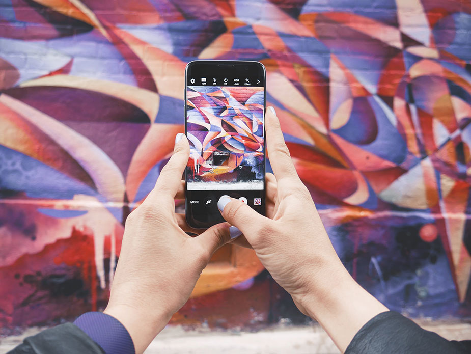 Person taking a photo of street art in Kensington Market