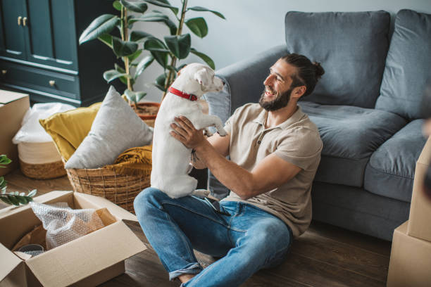 Young men moving in new house. He is happy and playing with his pet dog.