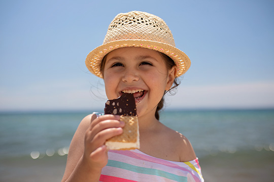 4-year-old girl having ice cream on a beach near the sea